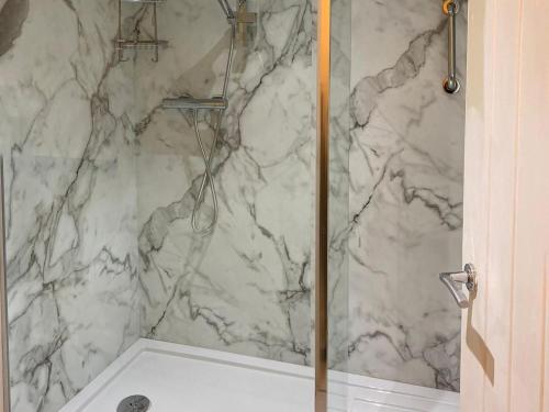 a bathroom with a shower with a marble wall at The Brooks in Crowan