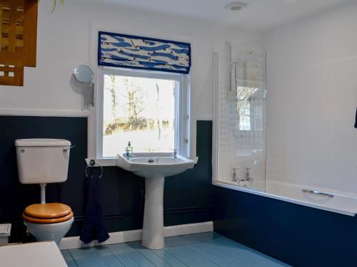 a bathroom with a sink and a toilet and a window at Straton Cottage in Saint Cyrus