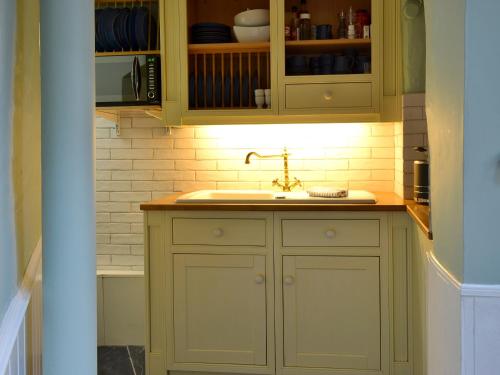 a kitchen with green cabinets and a sink at Anchor Cottage in Instow