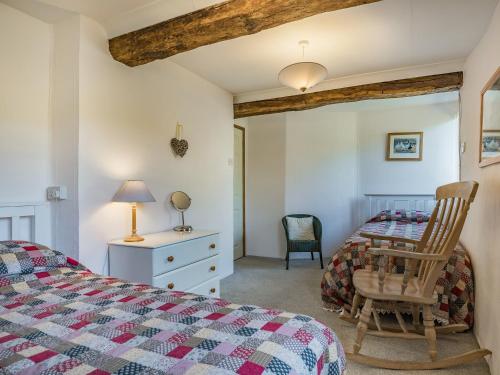 a bedroom with a bed and a desk and a chair at Clock Cottage in Branscombe