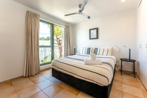 a bedroom with a bed and a large window at Onetangi Beach Apartments in Onetangi