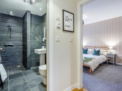 a bathroom with a bed and a sink and a toilet at Cliff Cottage in Kalnakill