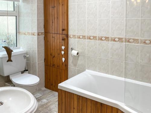 a bathroom with a tub and a toilet and a sink at Mill Head Cottage in Ilfracombe