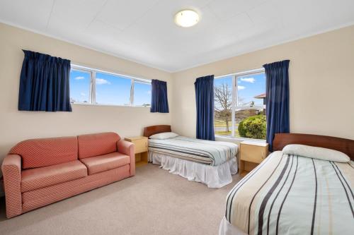 ein Schlafzimmer mit zwei Betten und einer Couch und einem Fenster in der Unterkunft The White House - Taupo Holiday Home in Taupo