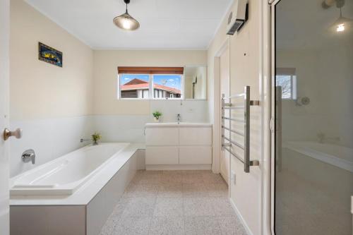 ein weißes Badezimmer mit einer Badewanne und einem Waschbecken in der Unterkunft The White House - Taupo Holiday Home in Taupo