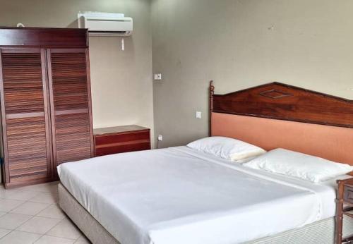 Schlafzimmer mit einem großen Bett mit einem Kopfteil aus Holz in der Unterkunft Hotel Ming Kiong 