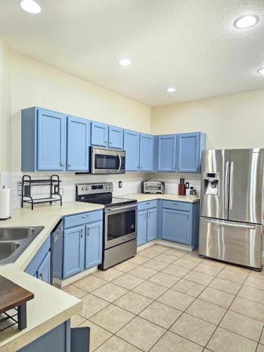 a kitchen with blue cabinets and stainless steel appliances at Cheerful 4bed 3bath with pool home near Disney in Kissimmee
