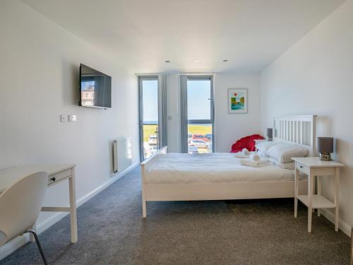 a bedroom with a bed and a desk and windows at Penthouse 47 Zinc in Newquay