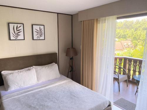 a bedroom with a bed and a balcony at Crosswinds Nature View Suite in Tagaytay