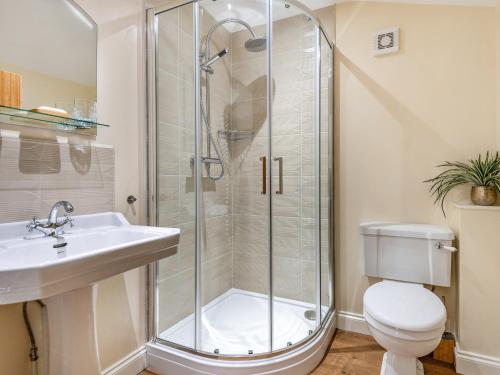 a bathroom with a shower and a toilet and a sink at Coach House in Rowston