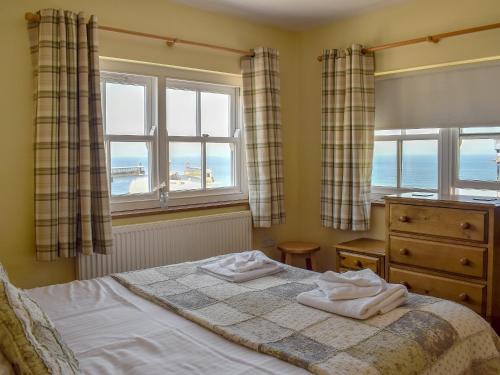 a bedroom with a bed and two windows at Captains Cottage - E3643 in Whitby