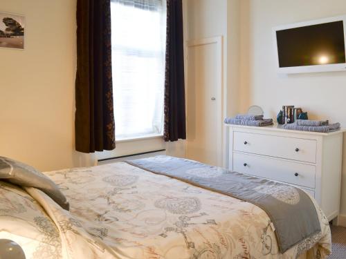 een slaapkamer met een bed, een dressoir en een raam bij Sunnyside in Filey