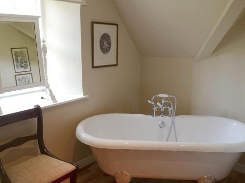 eine weiße Badewanne im Bad mit Fenster in der Unterkunft Tressady Coach House in West Langwell