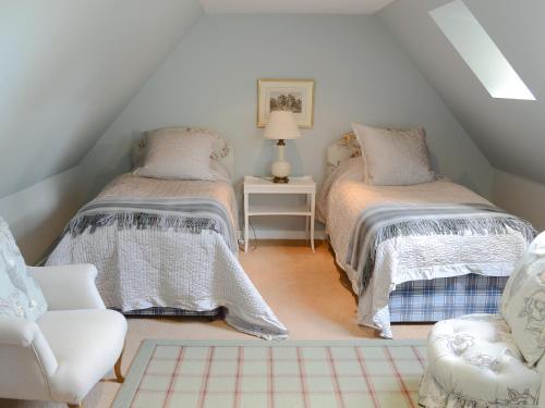 a attic room with two beds and a chair at Tressady Coach House in West Langwell