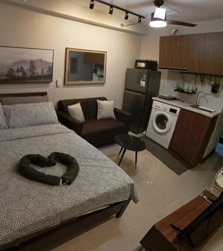 a room with a bed and a living room with a kitchen at Cozy Studio Apartment (Rm. 720) in Lapu Lapu City