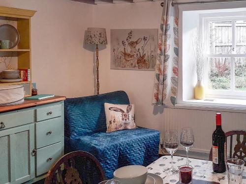 Freystrop的住宿－Woodlands Cottage，厨房配有蓝椅和带酒杯的桌子