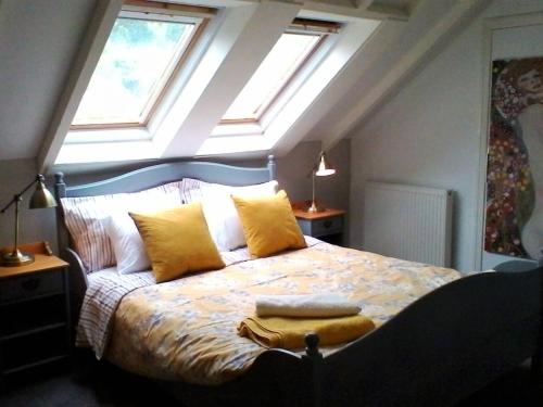 a bedroom with a bed with yellow pillows and windows at Stable Lodge in Gattonside