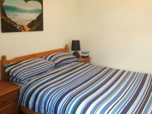 a bed with a blue and white striped comforter in a bedroom at The Cairngorms - Uk7096 in Contin