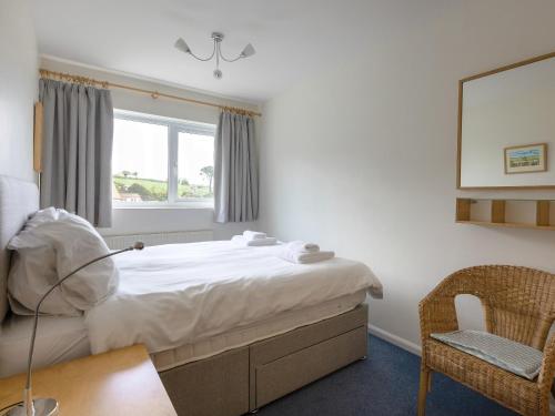 a bedroom with a bed and a chair and a window at Rockvale 1 in Salcombe