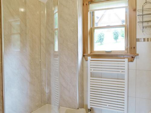 uma casa de banho com um chuveiro, uma janela e um WC. em Gilnockie em Kippford