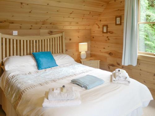 um quarto com uma cama num chalé de madeira em Gilnockie em Kippford