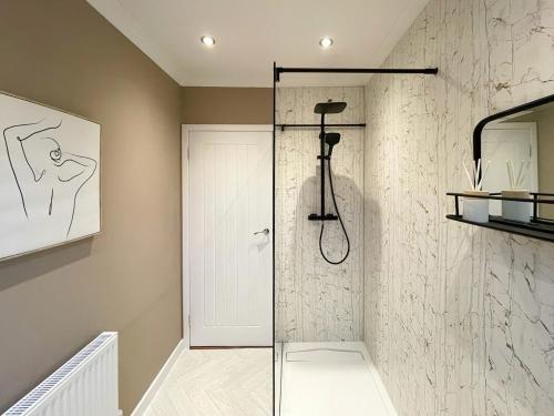 a shower with a glass door in a bathroom at Mossdale Cottage in Dalmellington