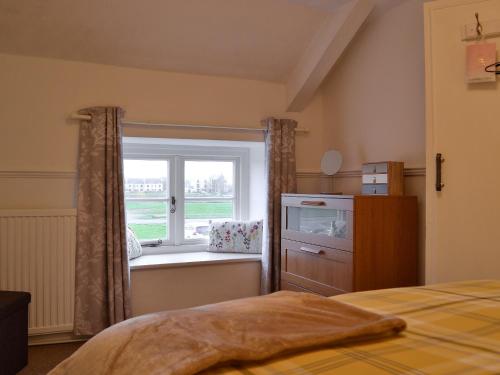 ein Schlafzimmer mit einem Fenster, einem Bett und einer Kommode in der Unterkunft Golwg Y Mor in Burry Port