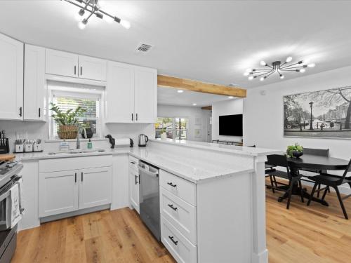 a white kitchen with white cabinets and a table at Cozy Arlington Bungalow 4/Mins to AT&T Stadium in Arlington