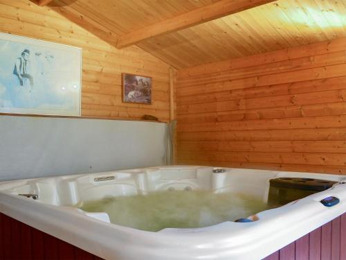 a large bath tub in a room with wooden walls at Carribber Beech in Torphichen