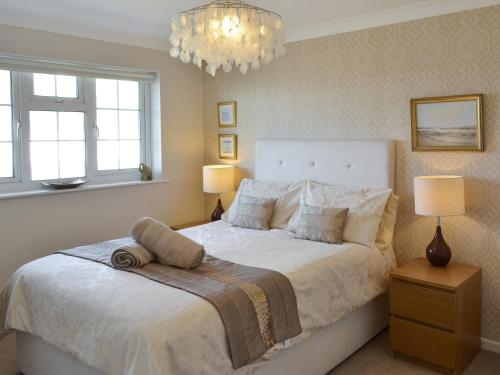 a bedroom with a bed and two lamps and a chandelier at Seagull Cottage in Portreath