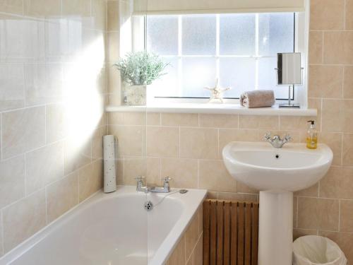 a bathroom with a bath tub and a sink at Seagull Cottage in Portreath