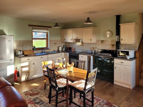 a kitchen with a wooden table and chairs and a kitchen with a stove at The Hen Hoose in Blainslie