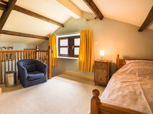 a bedroom with a bed and a chair and a window at Sundial Cottage in Gammersgill