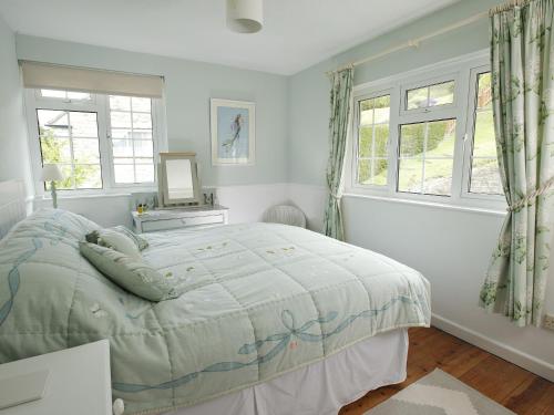 a bedroom with a bed and two windows at The Retreat Lulworth in West Lulworth
