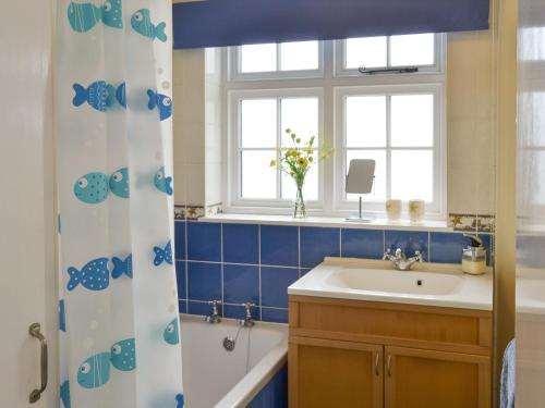 a bathroom with a sink and a tub and a window at Lighthouse Cottage in Happisburgh
