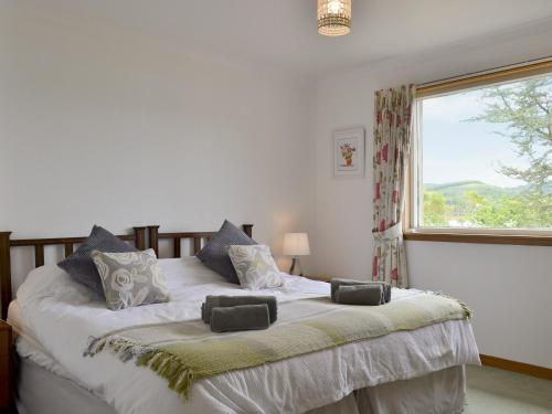 a bedroom with a large white bed with a window at Dunyvaig in Colintraive
