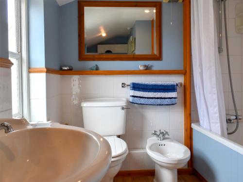 a bathroom with a tub and a toilet and a mirror at September Cottage in Wells next the Sea