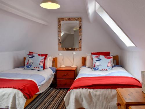 a attic bedroom with two beds and a mirror at September Cottage in Wells next the Sea
