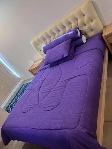 - un lit avec des draps et des oreillers violets dans l'établissement Grand Kamala Lagoon Bekasi Apartement, à Pekayon Satu