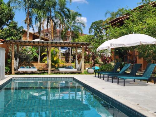 a swimming pool with two chairs and an umbrella at Confraria da Prata Flats in Pirenópolis