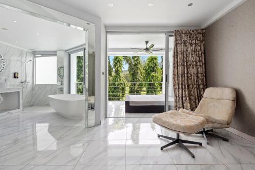 un bagno con vasca, sedia e finestra di The Fairways Villas - 5 bedrooms & bathroom for up to 14 guests 7kms to Patong a Kathu