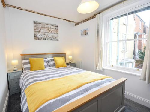 a bedroom with a bed with yellow pillows and a window at Hawkes Lane in Canterbury