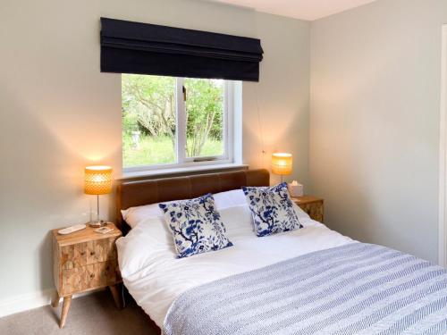 a bedroom with a bed with two pillows and a window at Rose Cottage in Blakemere