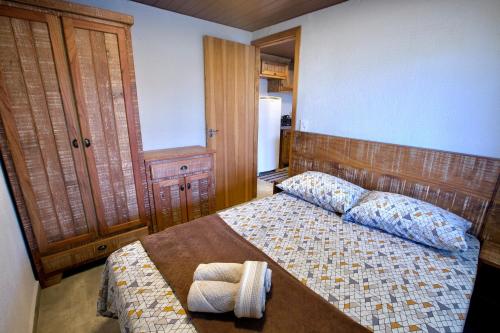 Schlafzimmer mit einem Bett mit einem Kopfteil aus Holz in der Unterkunft Chalé do Litoral in Penha