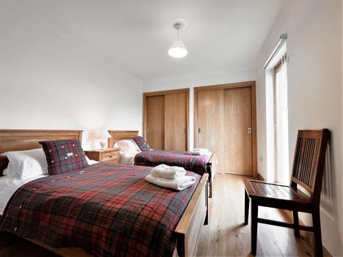 a bedroom with two twin beds and a chair at Taigh Nan Eilean in Valtos