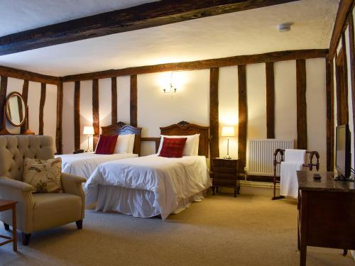 a hotel room with two beds and a chair at The Old Bakery in Pulham Saint Mary Magdalene