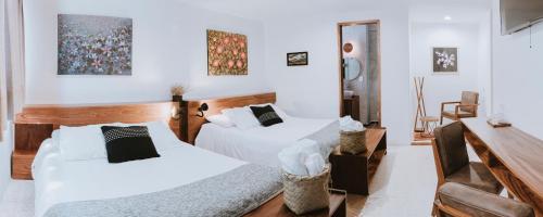 Habitación con 2 camas, paredes blancas y escritorio. en Hotel Boutique Casa de Arte Oaxaca, Art Gallery & Pool, en Oaxaca City