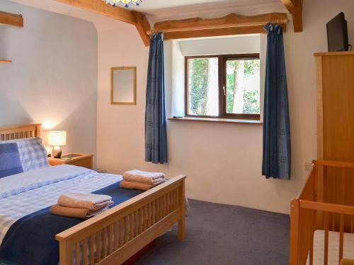 a bedroom with a bed with blue curtains and a window at Coachmans Retreat in Saint Kew