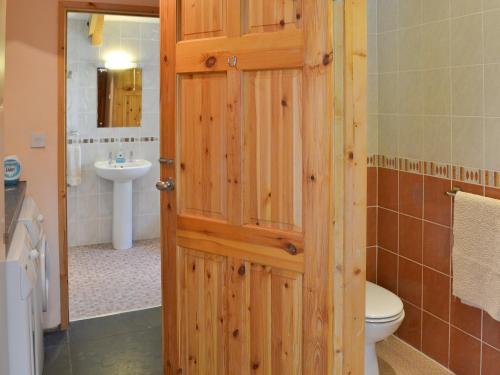a bathroom with a wooden door and a sink at Coachmans Retreat in Saint Kew
