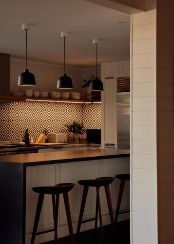 a kitchen with two bar stools and a counter at 28 Degrees Byron Bay - Adults Only in Byron Bay